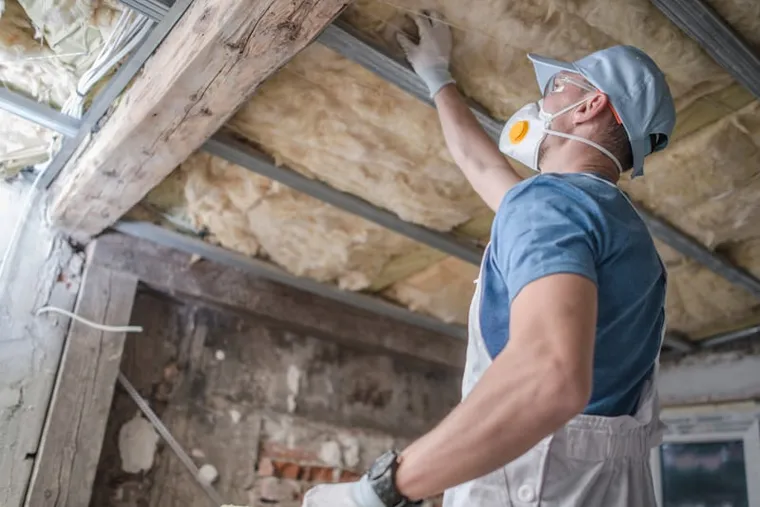 Building professional inspecting insulation and moisture conditions
